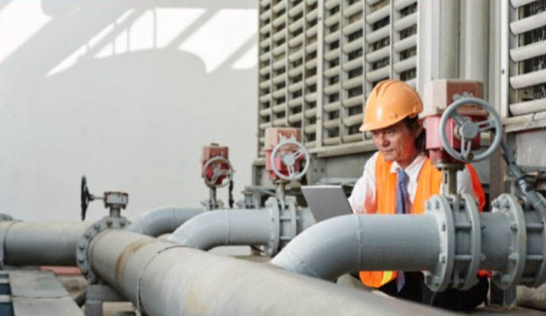 engineer looking at large water pipes